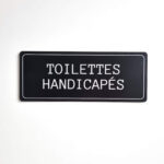 Plaque de porte toilettes handicapés en plastique de couleur noir fixation par adhésif